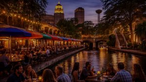 People dining along the San Antonio River Walk with city landmarks in the background